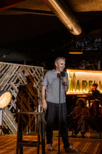 T-shirt gris La Marelle Comedy Club Bordeaux porté par un humoriste, logo œil qui sourit au cœur