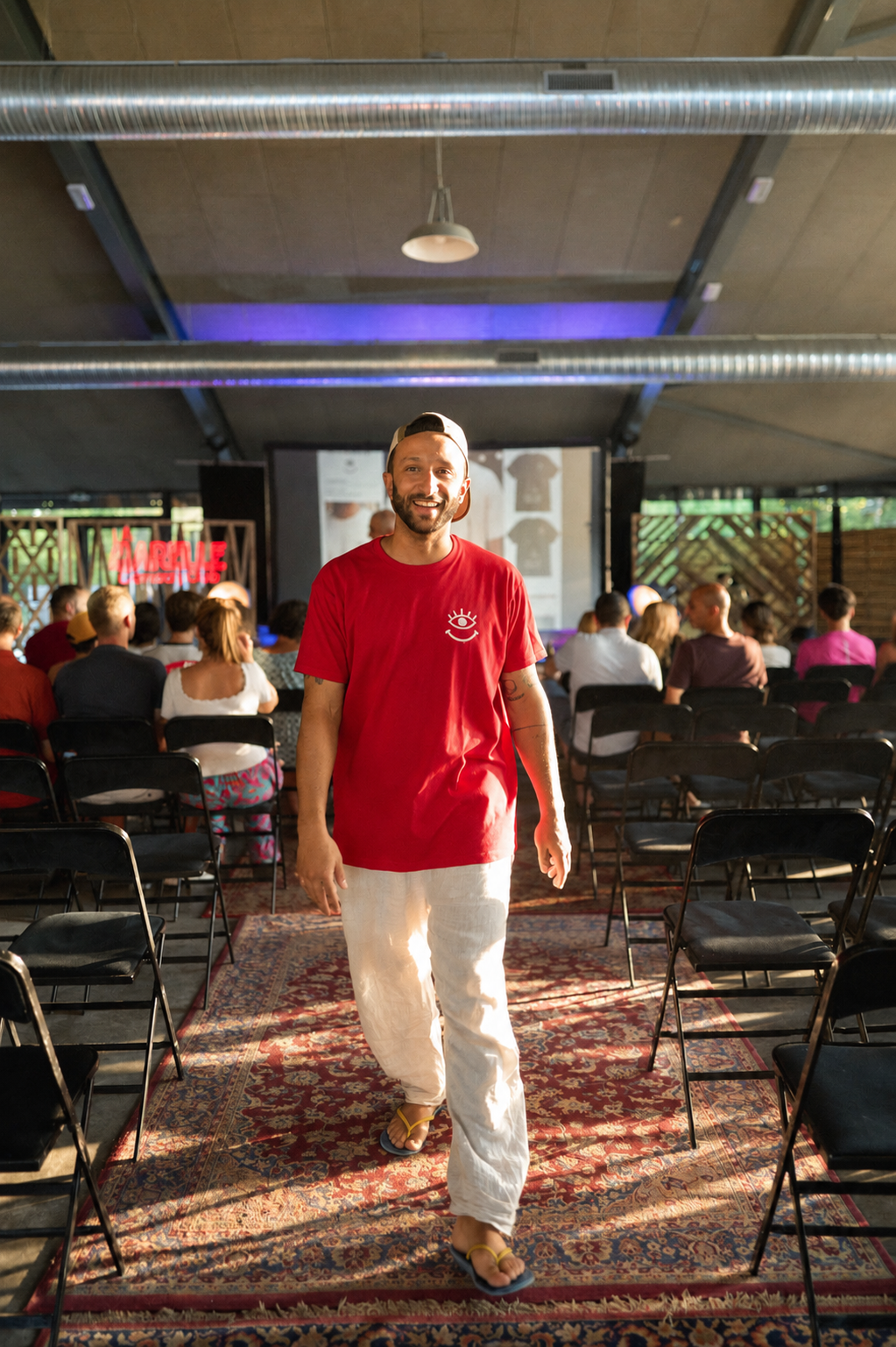 T-shirt rouge La Marelle Comedy Club Bordeaux porté par un humoriste, logo œil qui sourit au cœur